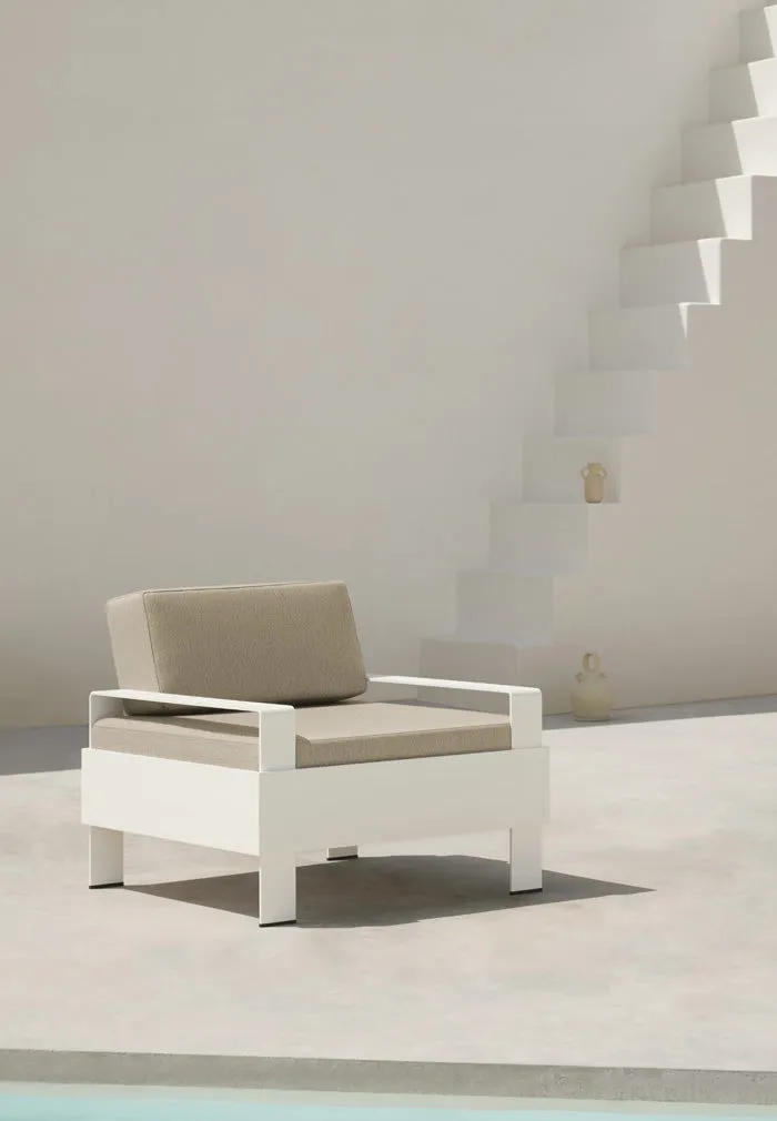 White Zenttal armchair with beige cushions beside a white staircase